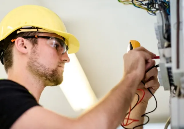 ¿Sin luz? ¿Huele a quemado, saltan los plomos o ves chispas? Electricista con casco y gafas midiendo con pinza amperimétrica en Málaga