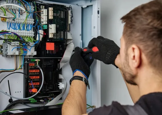 Electricista en Málaga que te lo resuelve hoy Electricista con guantes revisando el cableado de un cuadro eléctrico de vivienda · Electricista en Málaga que te lo resuelve hoy