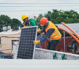 Placas solares Instaladores con casco colocando un panel solar en una azotea